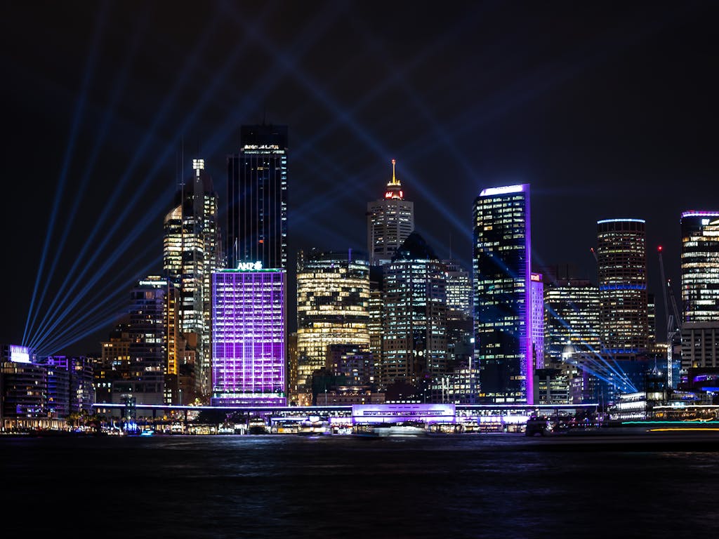 A vibrant night view of Sydney's illuminated skyline with modern architecture and bright city lights.