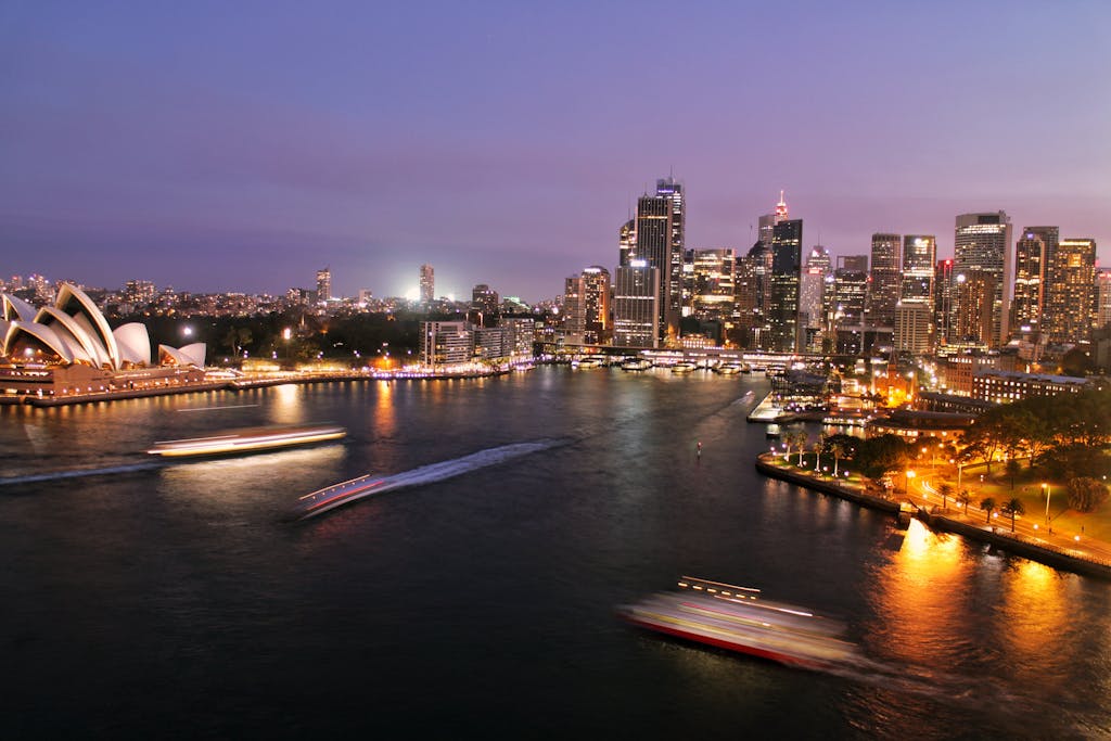 Captivating view of Sydney's illuminated skyline with the iconic Opera House and harbor at night.